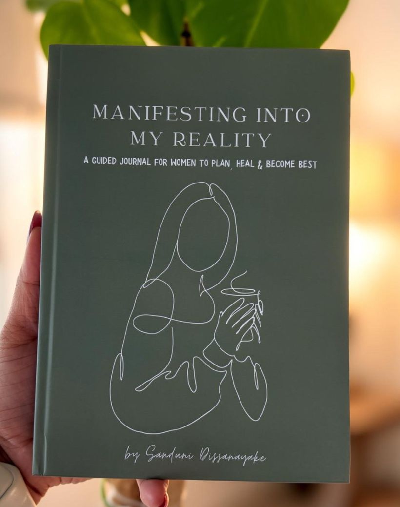The sage green Manifesting Into My Reality journal with a line drawing of a woman holding a cup, by Sanduni Dissanayake